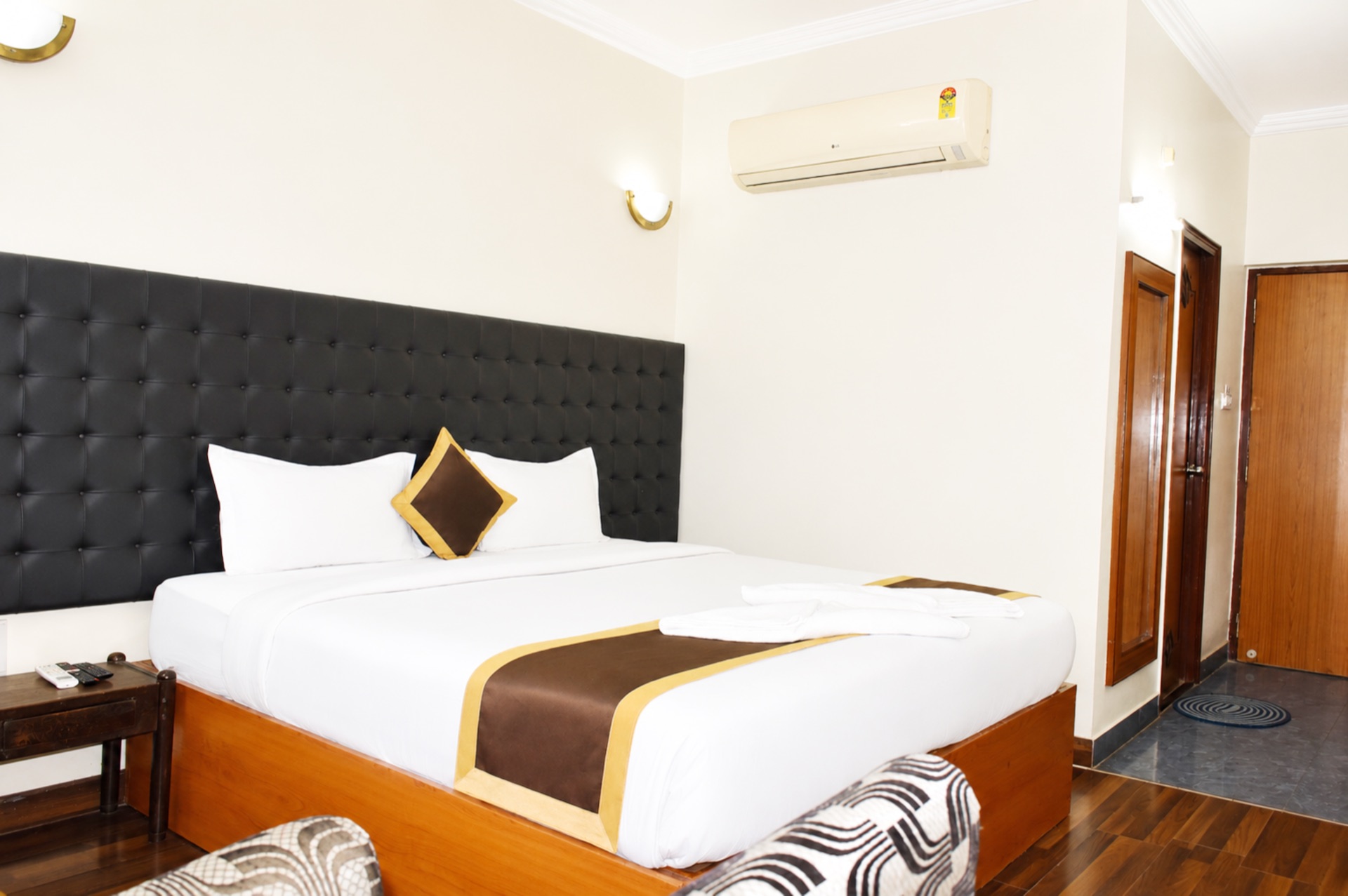 AC Deluxe room interior view with split AC, side table and wooden flooring