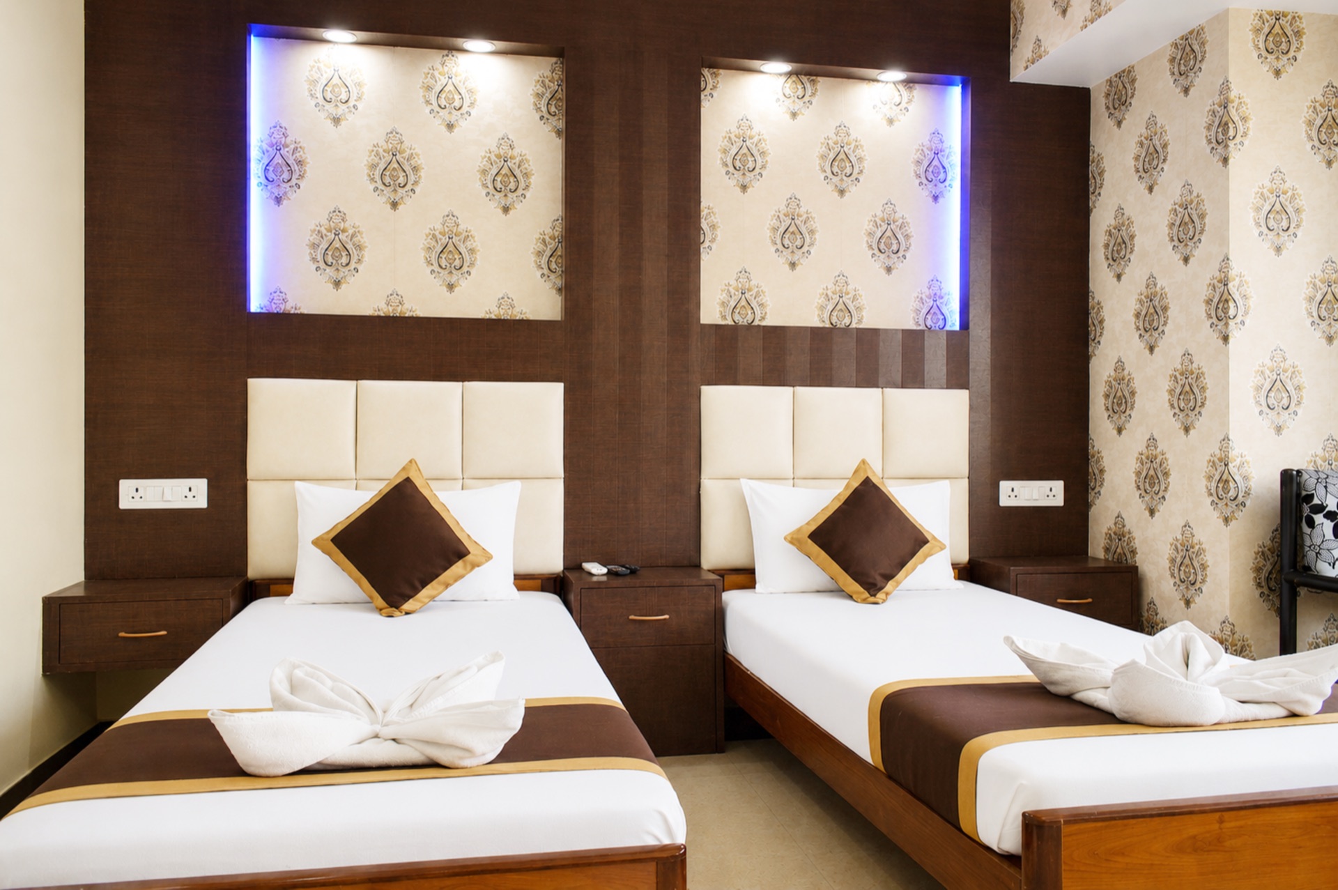 AC Executive twin beds with padded headboards and decorative wallpaper